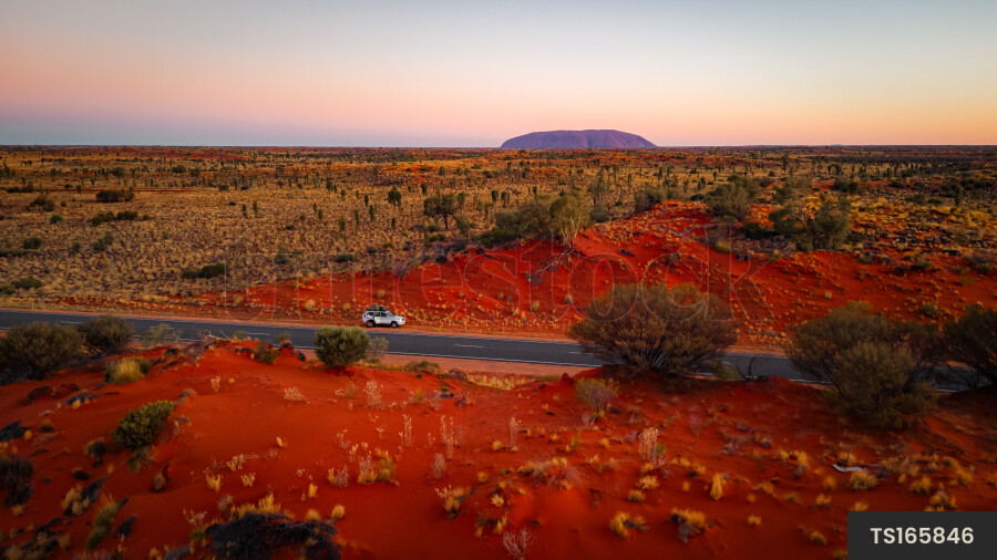 Car next to road in landscape during sunset