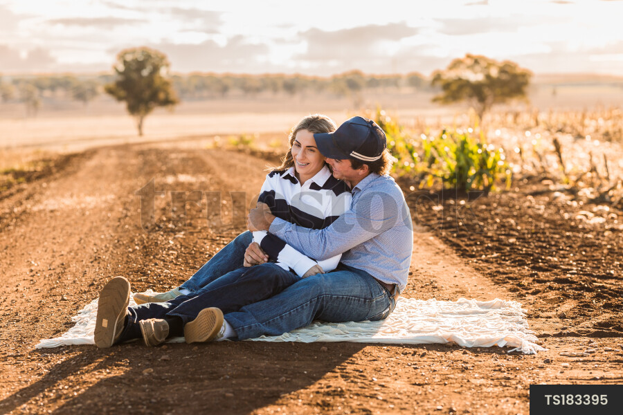 Couple sitting on picnic blanket on dirt road
