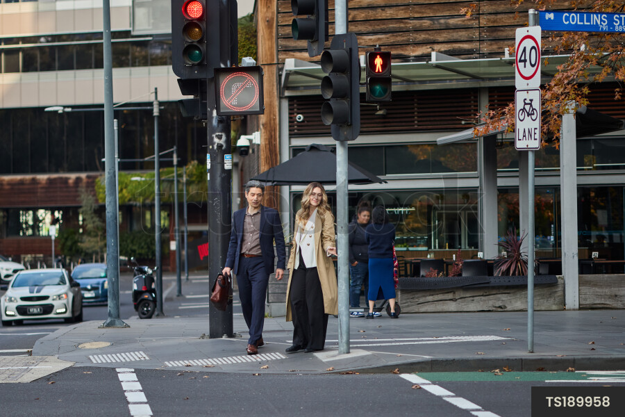 Two adults standing at road crossing in city