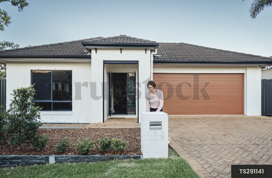 Woman checking mail in letterbox outside house