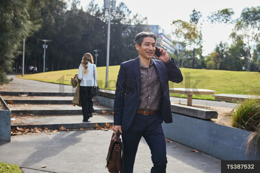 Man talking on phone while walking in city park