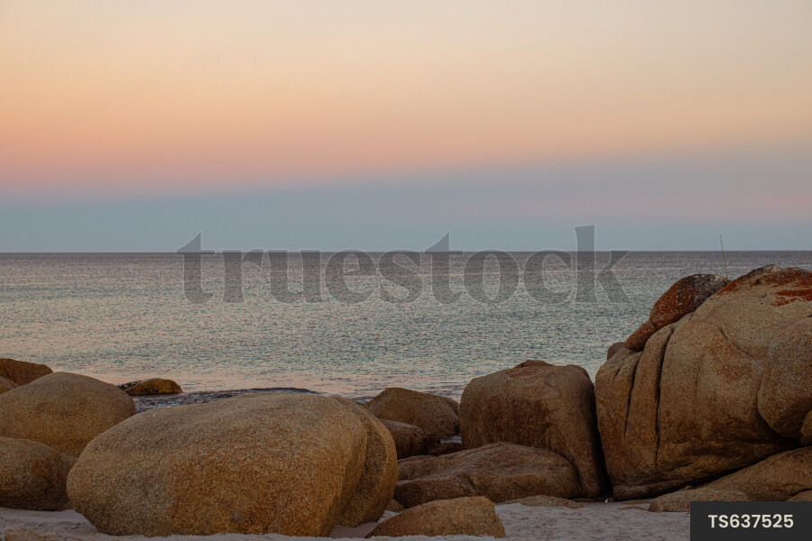 Rock on beach at sunset