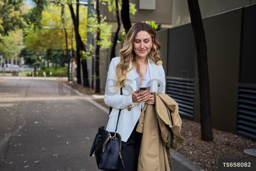 Happy woman texting on phone while walking 
