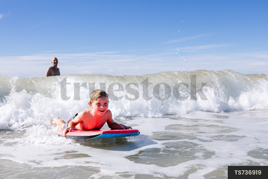 Boy playing with body board on beach