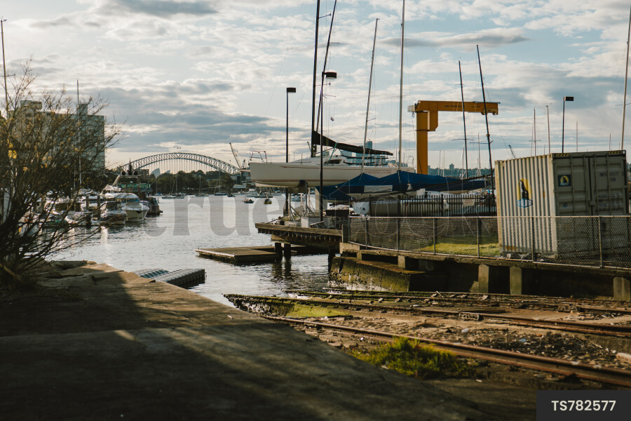 Boats in harbour by boat yard under clouds