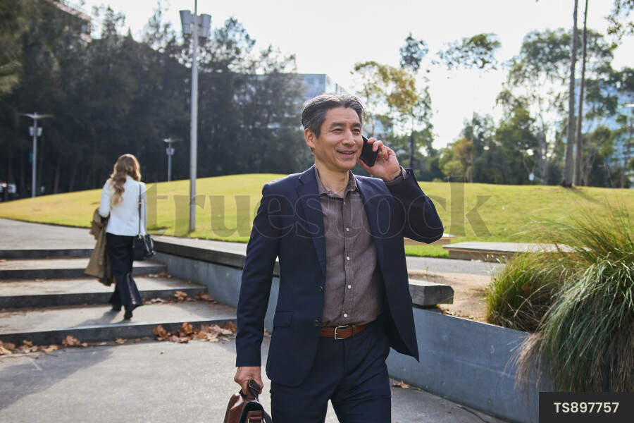 Man talking on phone while walking in city park