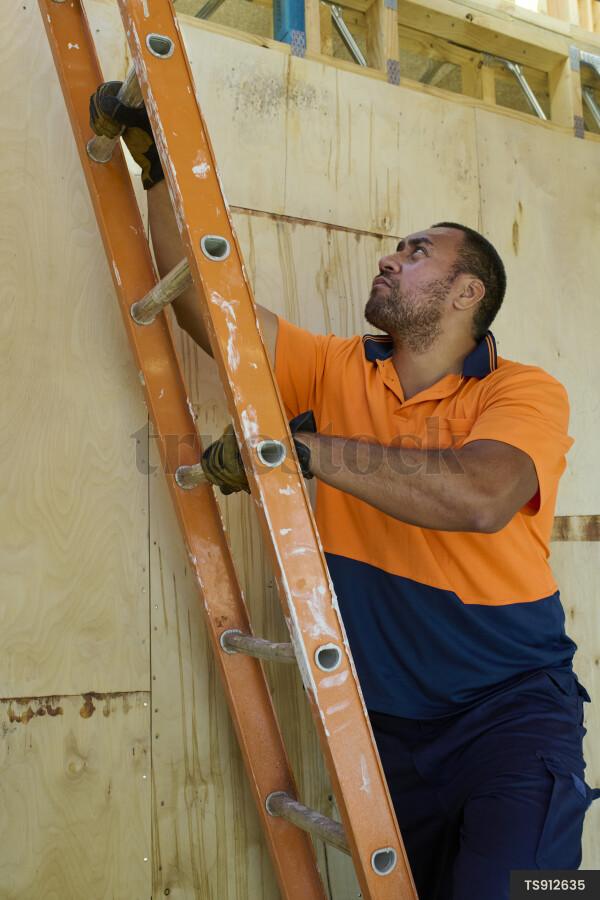 TS912635 Construction worker climbing a ladder at a construction site ...