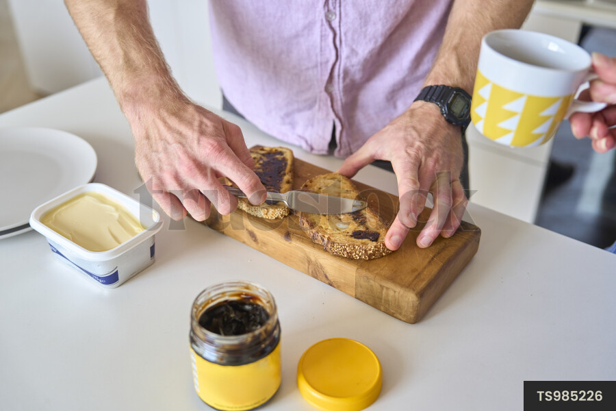 Hands of man spreading vegemite on toast